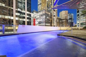 An indoor swimming pool with a view of high-rise buildings at night. - Arcade in the Sky - Views, Games & Vibes (Brisbane)