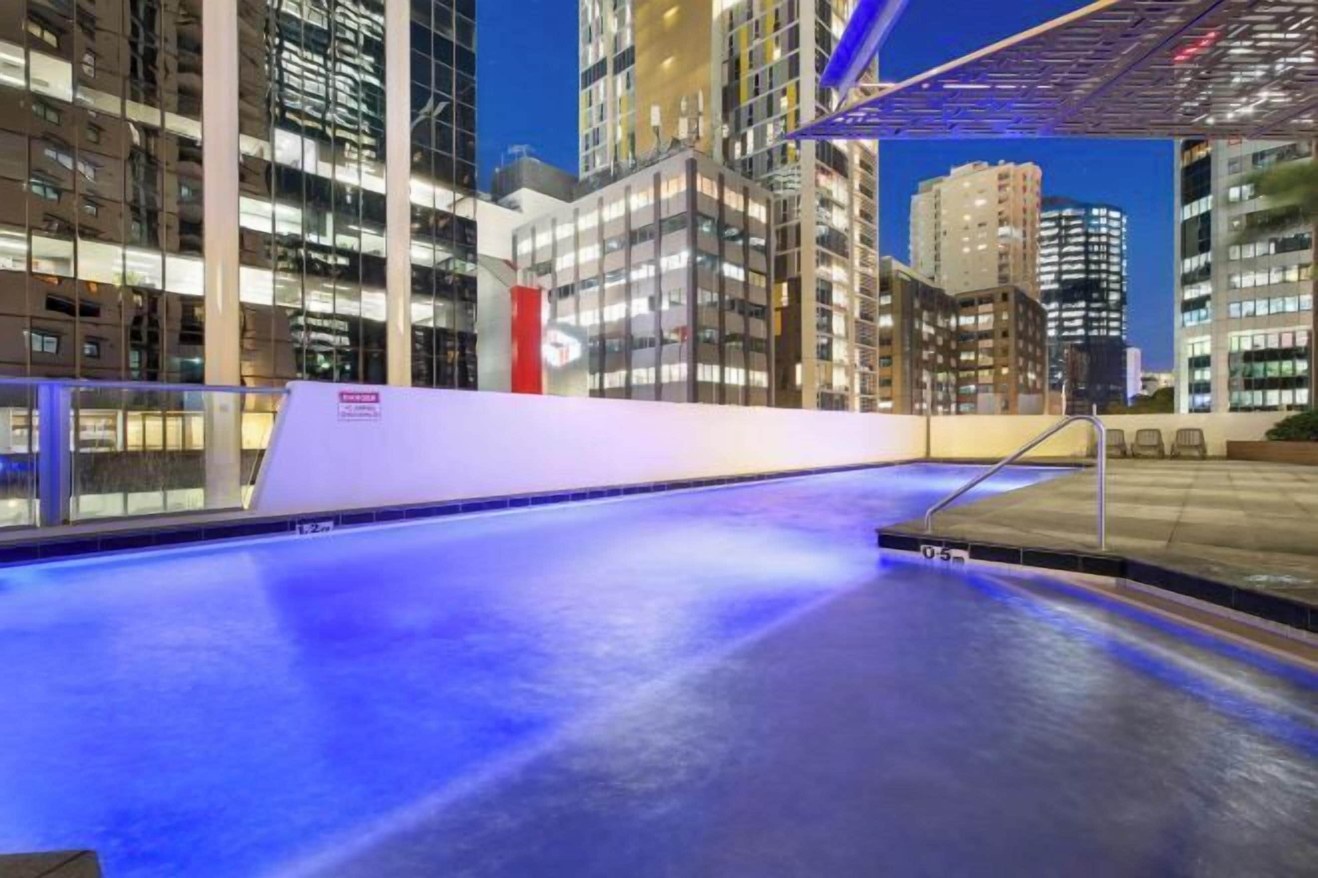 An indoor swimming pool with a view of tall buildings at night.