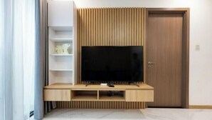 Un salon moderne doté d’un téléviseur encastré, de lambris en bois et d’une étagère blanche.