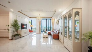 A spacious living room with a modern design, featuring a large sofa, a TV, and a decorative cabinet.