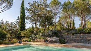 A rectangular pool with clear water, surrounded by a stone wall and various trees. - Domaine 20 people with swimming pool, spa and tennis (Saint-Julien-les-Rosiers)