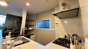 A modern kitchen with a gas stove, a window, and a built-in oven. - Haku Wakanayanagi Inn (Kyoto)
