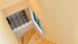 A wooden staircase with a metal railing, leading to a landing with a window. - Haku Wakanayanagi Inn (Kyoto)