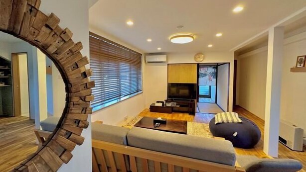 A modern living room with a wooden-framed mirror, a sofa, a coffee table, and a television. - Haku Wakanayanagi Inn (Kyoto)