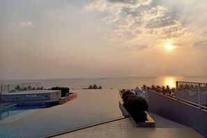 Una piscina en la azotea con vistas a la puesta de sol sobre el océano.