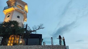 Ein Steinturm mit einem Balkon, eine Steinmauer und eine Person, die eine Taschenlampe hält.