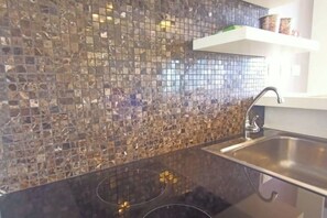 A kitchen with a mosaic backsplash and a stainless steel sink. - Baan Chid Haad (Chon Buri)