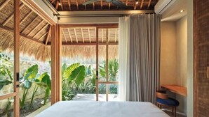 A bedroom with a bed, a ceiling fan, a window with curtains, and a view of greenery. - Boni Beach Lombok Hotel & Restaurant (West Praya)