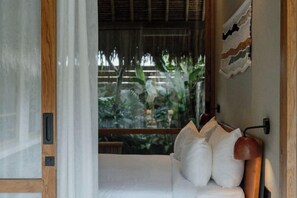 A room with a bed, pillows, a lamp, and a view of greenery outside. - Boni Beach Lombok Hotel & Restaurant (West Praya)