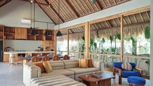 A spacious living area with a large sofa, a coffee table, and a dining area with chairs. - Boni Beach Lombok Hotel & Restaurant (West Praya)