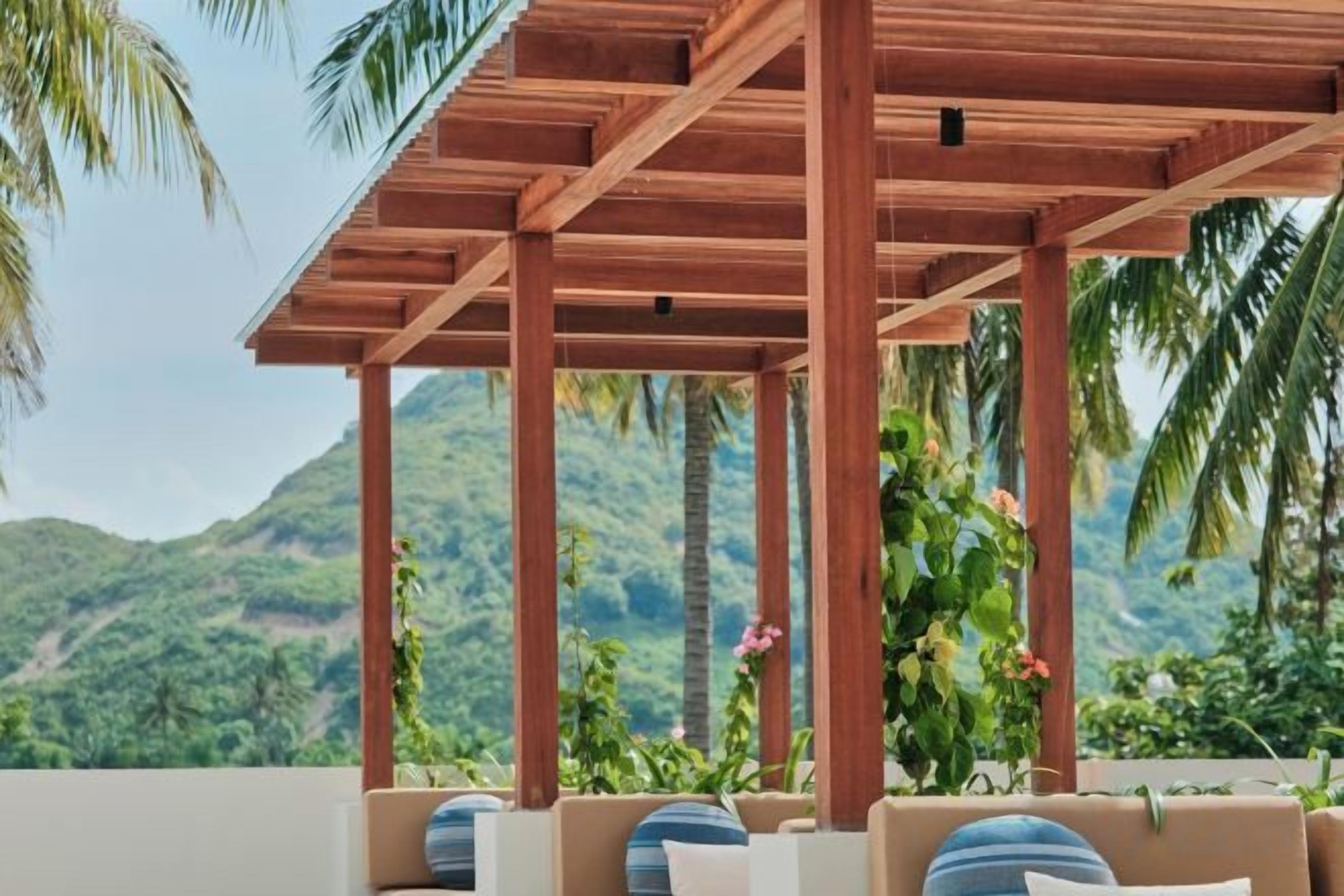 Una estructura de pérgola de madera con asientos, con vistas a un paisaje montañoso.