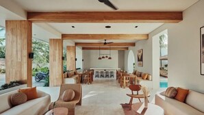 A spacious living area with a high ceiling, wooden beams, and a central seating area with sofas and chairs. - Boni Beach Lombok Hotel & Restaurant (West Praya)