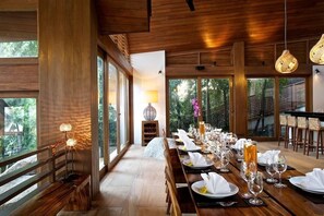 A long dining table set for a meal with a view of the outdoors. - Baan Hinta (Koh Samui)