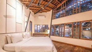 A bedroom with a bed, wooden flooring, large windows, and a sloped ceiling. - BAz Penthouse (Bali)