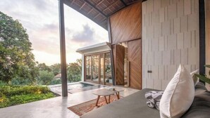 A modern outdoor living area with a sofa, a small table, and a view of a swimming pool. - BAz Penthouse (Bali)