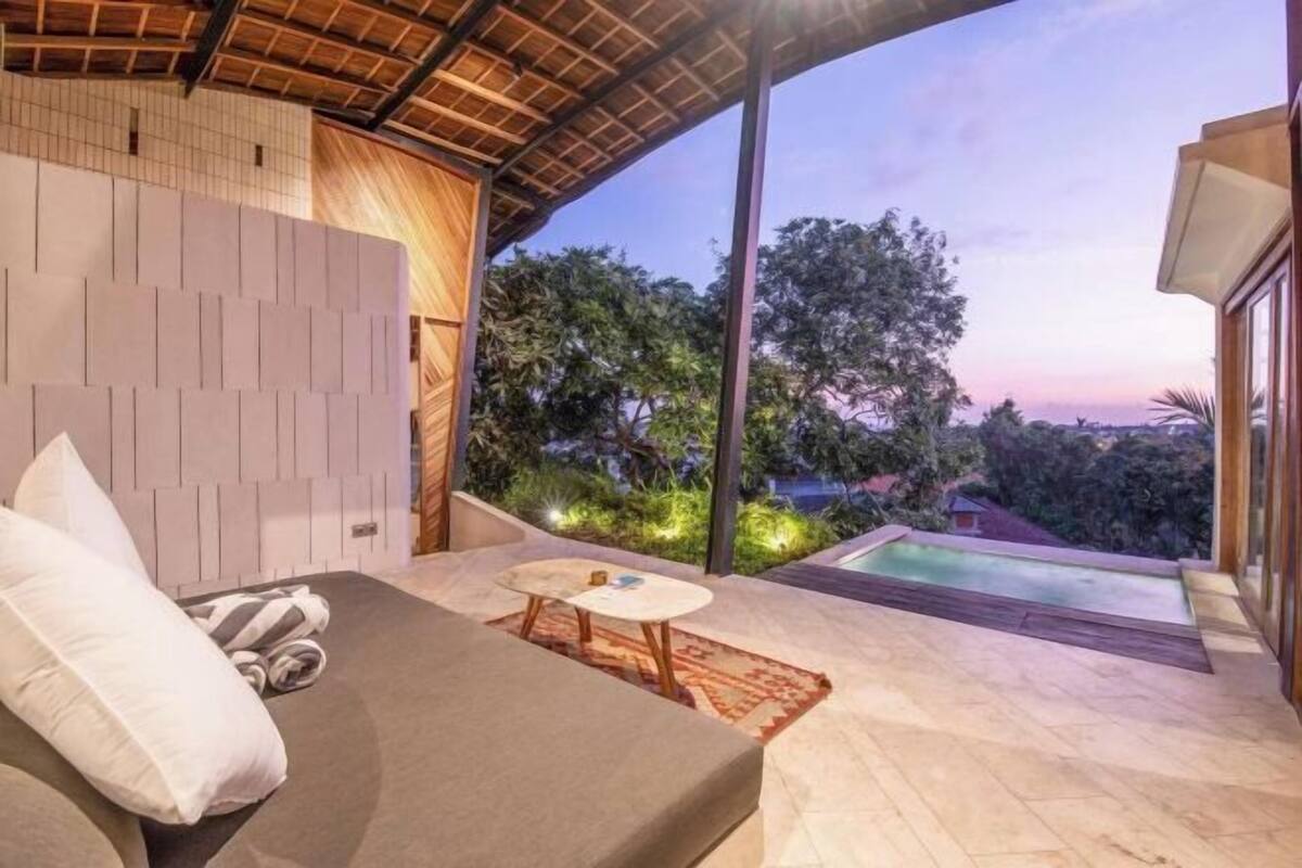 A modern room with a bed, a small table, and a view of a swimming pool.