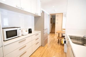 A modern kitchen with white cabinets, a microwave, a coffee maker, and a stainless steel sink.