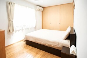 Ein Schlafzimmer mit einem Bett, einem Holzschrank und einem Fenster mit Vorhängen.