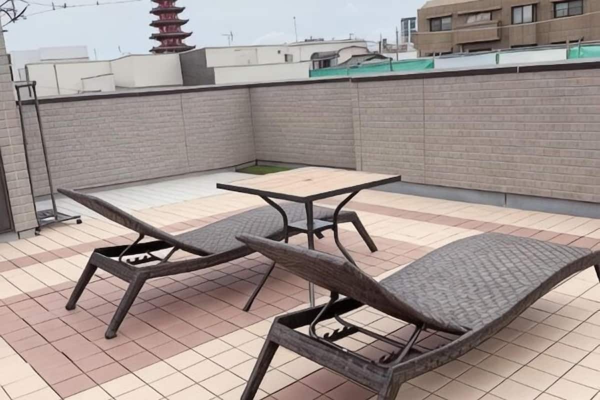 A rooftop patio with a table and two lounge chairs.