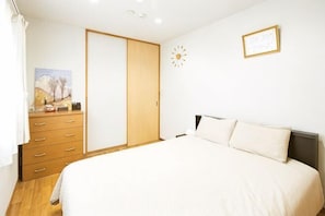 A bedroom with a bed, a dresser, a wardrobe, a clock, and a framed picture on the wall.