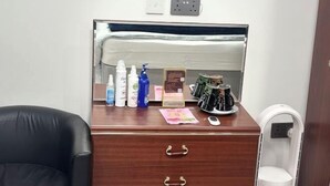 A wooden desk with toiletries, a mirror, and a coffee maker. - Min Su Rooms (Stanwell)