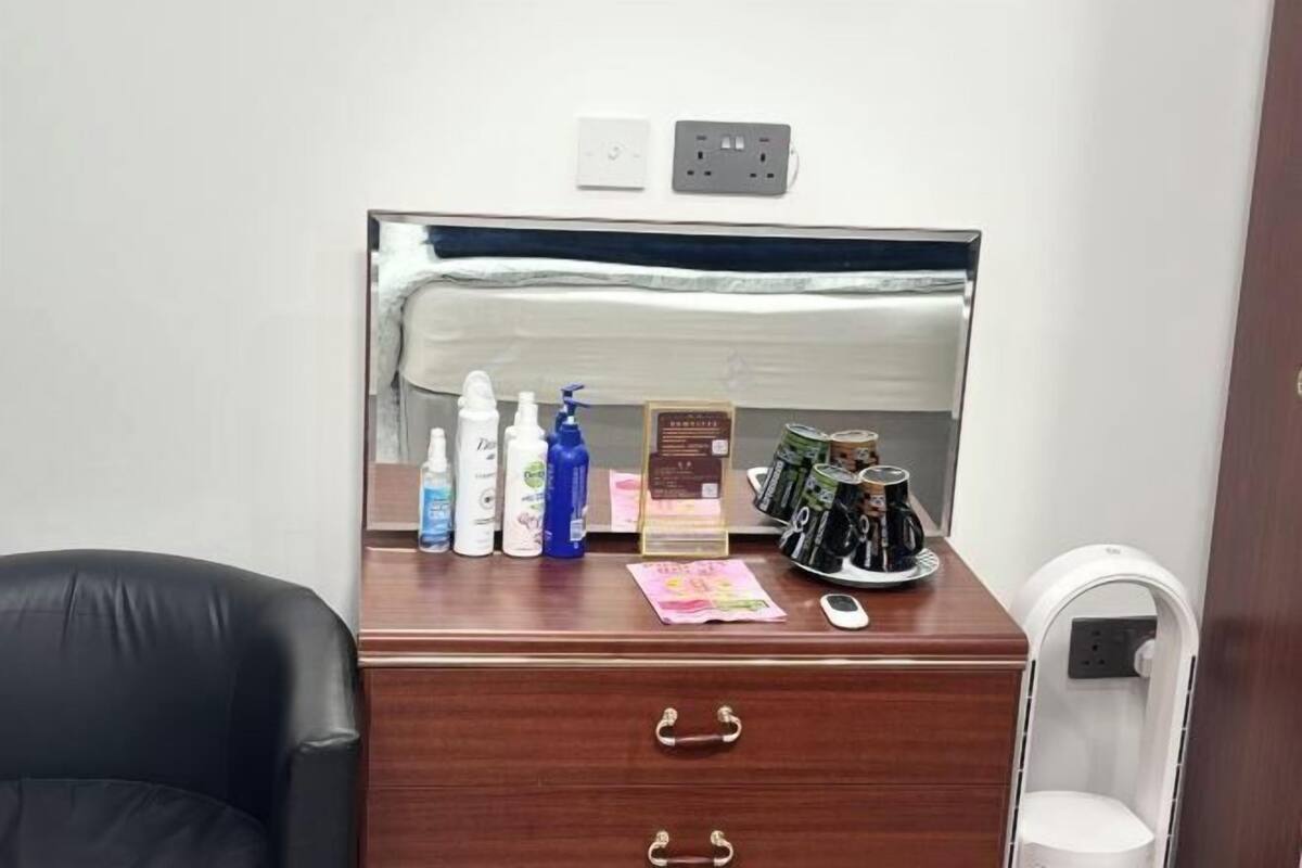 A wooden desk with toiletries, a mirror, and a coffee maker.