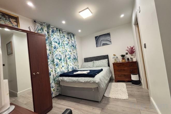 A bedroom with a bed, a dresser, a mirror, and a door.