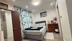 A bedroom with a bed, a dresser, a mirror, and a door. - Min Su Rooms (Stanwell)