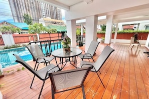 A covered outdoor area with a pool, seating, and a view of a cityscape.