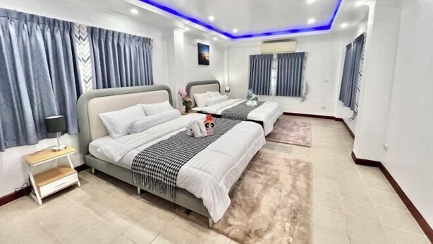A modern hotel room with two beds, a nightstand, a lamp, and a large window with curtains. - Casa jomtien village Pattaya Sea Sky Pool Villa (Pattaya)