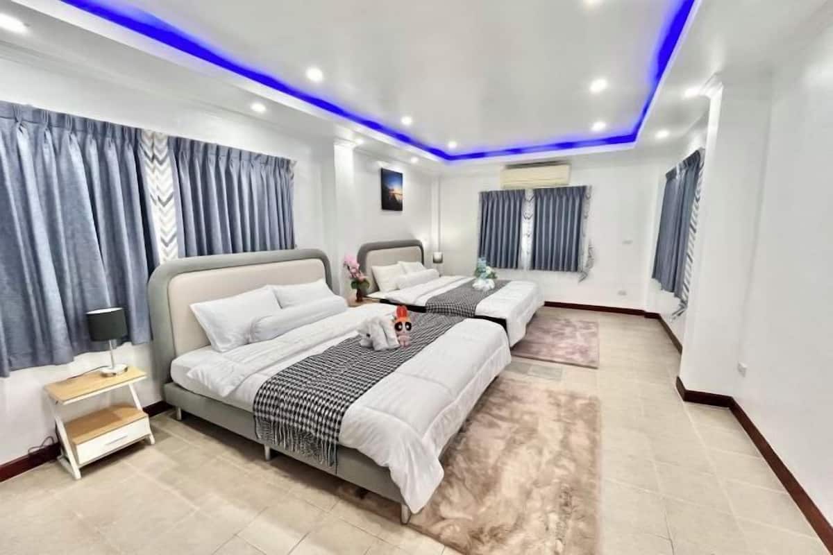 Ein modernes Hotelzimmer mit zwei Betten, einem Nachttisch, einer Lampe und einem großen Fenster mit Vorhängen.