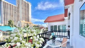 A balcony with a table and chairs, a railing, and a view of tall buildings. - Casa jomtien village Pattaya Sea Sky Pool Villa (Pattaya)