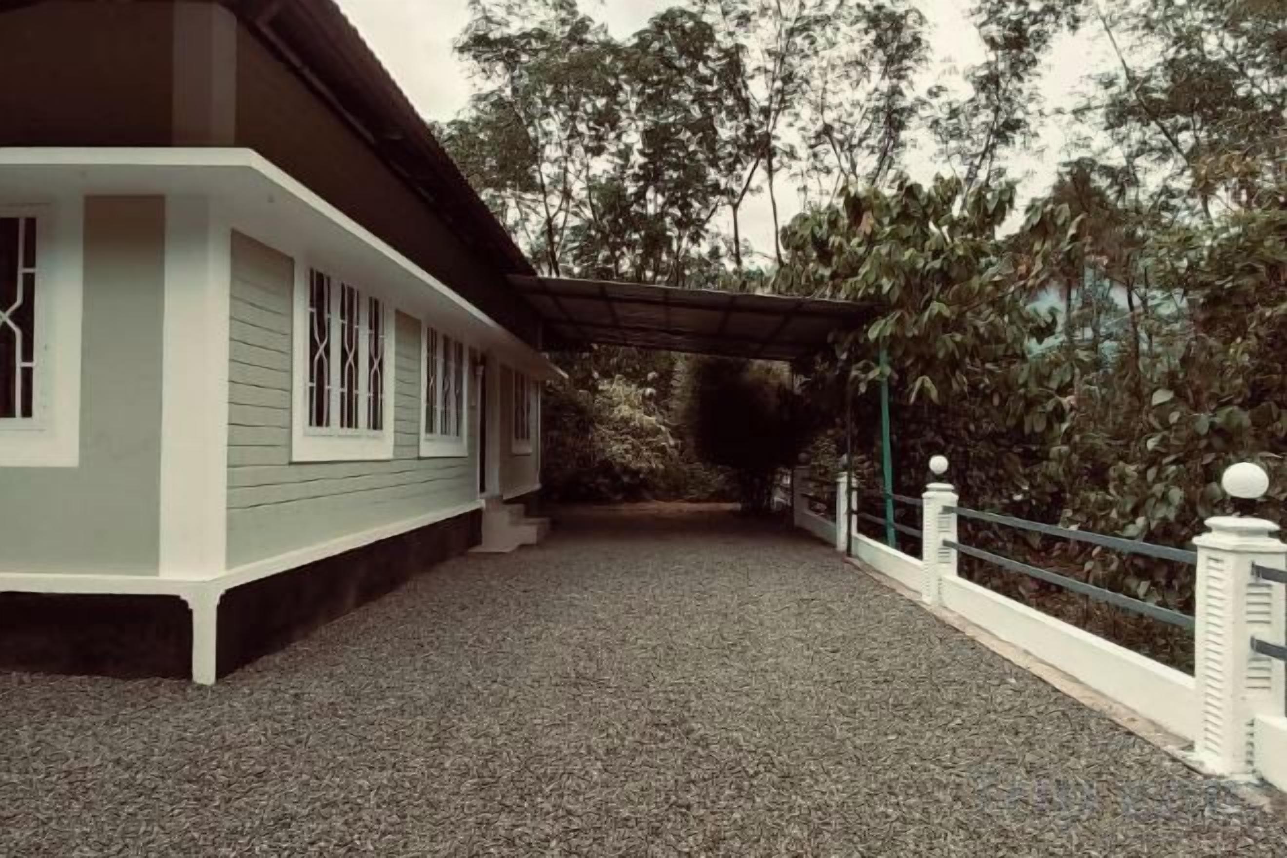 A building with a covered porch, gravel ground, and a white fence.