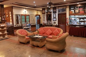A lobby with wicker furniture, a reception desk, and a display of items. - Phukhamsaed chiangrai (Chiang Saen)