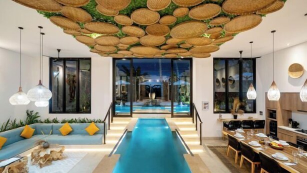 A modern interior with a central water feature, a dining area, and a seating area with a blue sofa and yellow cushions.
