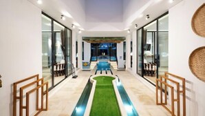 A modern hotel lobby with a central pool, glass walls, and wooden furniture.