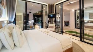 A modern hotel room with a large bed, a TV, and a view of a pool and outdoor area through glass doors.