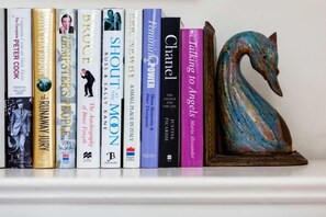 A bookshelf with books and a decorative swan. - Steps to Sloane Square (London)
