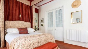 Un dormitorio con cama, una banca, una puerta y un espejo en la pared.