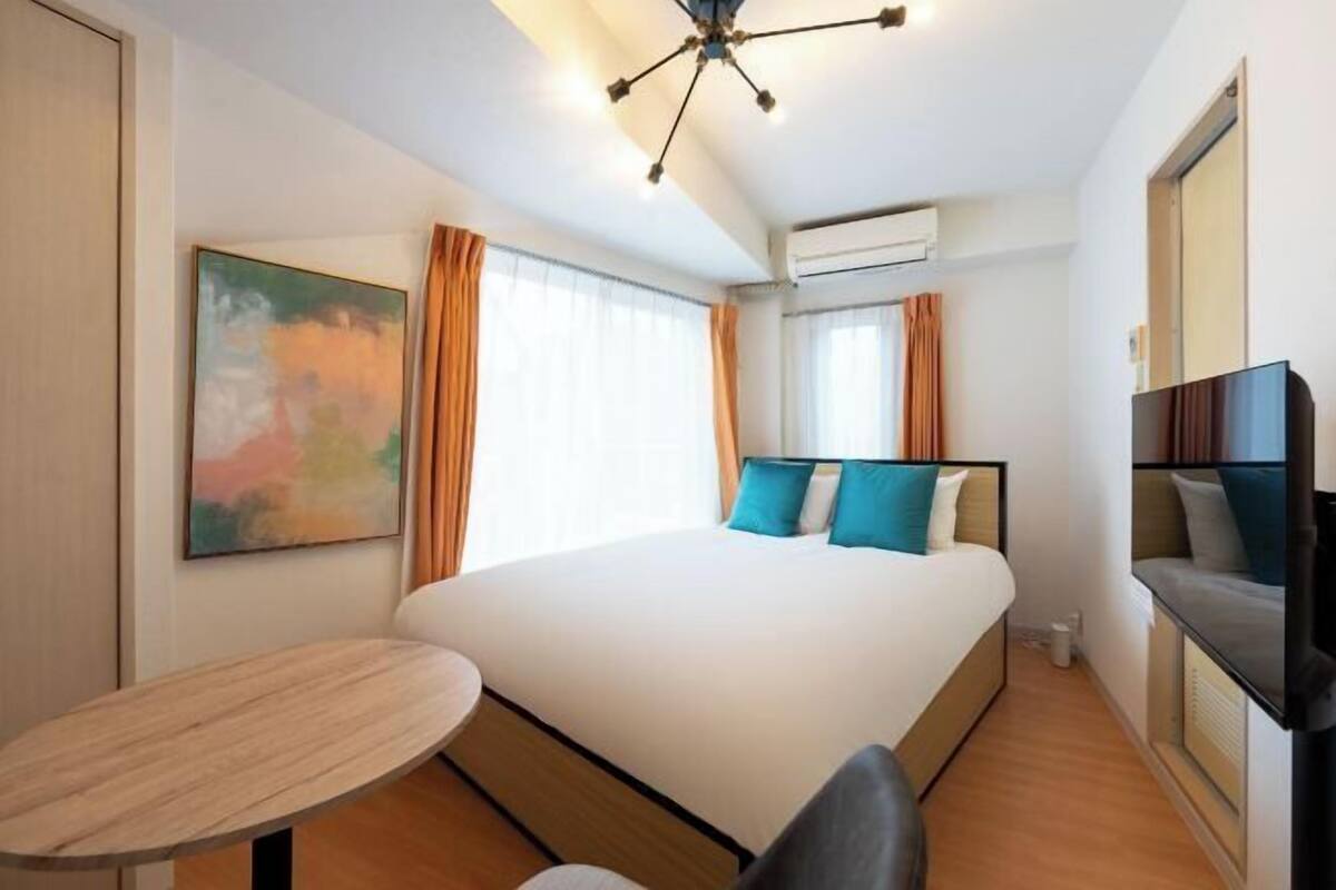 Une chambre d’hôtel avec un grand lit, une petite table, une télévision et un tableau au mur.