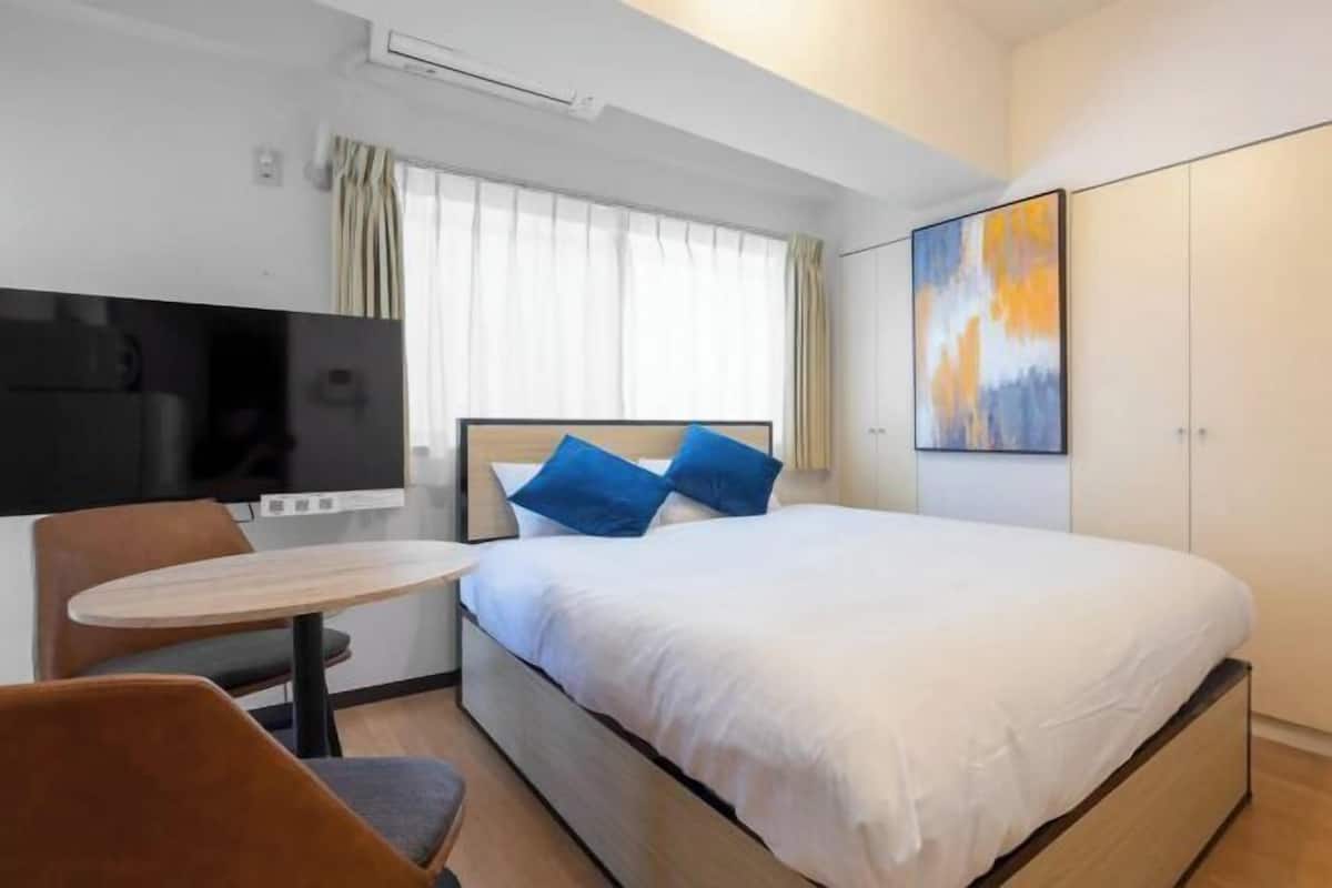 Une chambre d’hôtel moderne, équipée d’un lit, d’une petite table et d’un téléviseur.