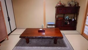 A traditional Japanese room with tatami flooring, a wooden table, and a low shelf with decorative items. - Private Villa Gifu Takayama (Takayama)