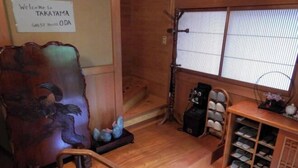 A traditional Japanese room with a wooden floor, a carved wooden chair, a shoe rack, and a sliding door with a view of the outside. - Private Villa Gifu Takayama (Takayama)
