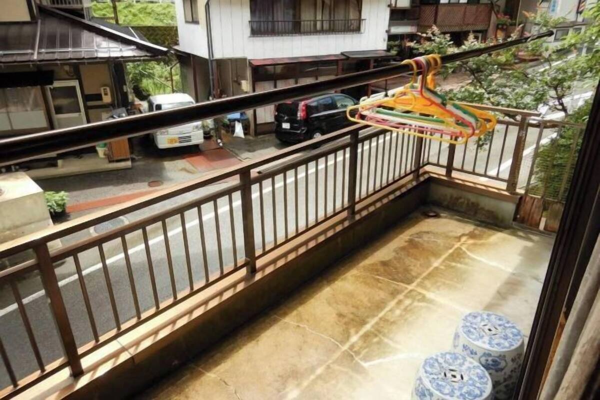A balcony with a metal railing, a small table, and two blue patterned stools.