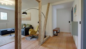 A modern living room with a wooden floor, a sofa, a yellow chair, a round table, and a floor lamp. - Stylish vacation apartment in Germany's highest train station (Feldberg (Schwarzwald))