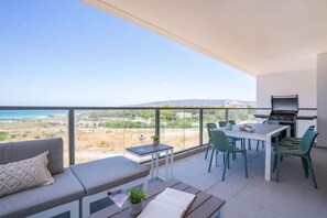 A balcony with a dining area, a sofa, and a grill. - Stylish Seaside Escape with Balcony (Nahariyya)