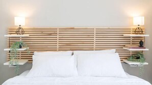 A bed with white bedding, two bedside tables with lamps, and wooden slats on the headboard. - Stylish Seaside Escape with Balcony (Nahariyya)