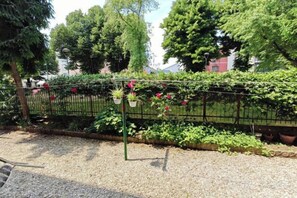 A garden with a metal fence, potted plants, and a gravel path. - Casa di Serena (Venice)