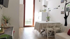 A dining area with a table and chairs, a TV mounted on the wall, and a door leading to an outdoor area. - Casa di Serena (Venice)