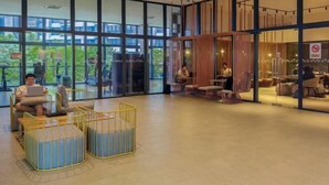A spacious lobby with large windows, seating areas, and a visible restaurant section.